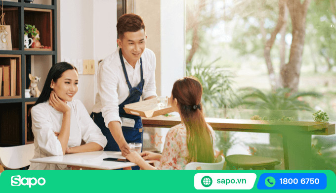 Nhân viên phục vụ cẩn thận mang đồ uống ra bàn cho khách
