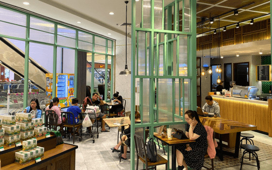 Khung cảnh bên trong quán Phúc Long với không gian hiện đại và bàn ghế gỗ